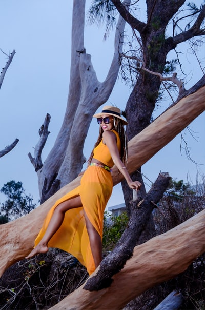 穿黄色衣服的女人白天爬在棕色的树上